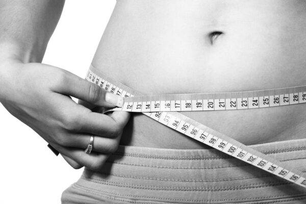A photo of a woman measuring her waist.