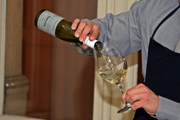 A photo of a sommelier pouring wine.