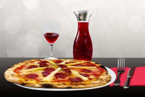 Photo of a pizza with wine glasses and bottle.