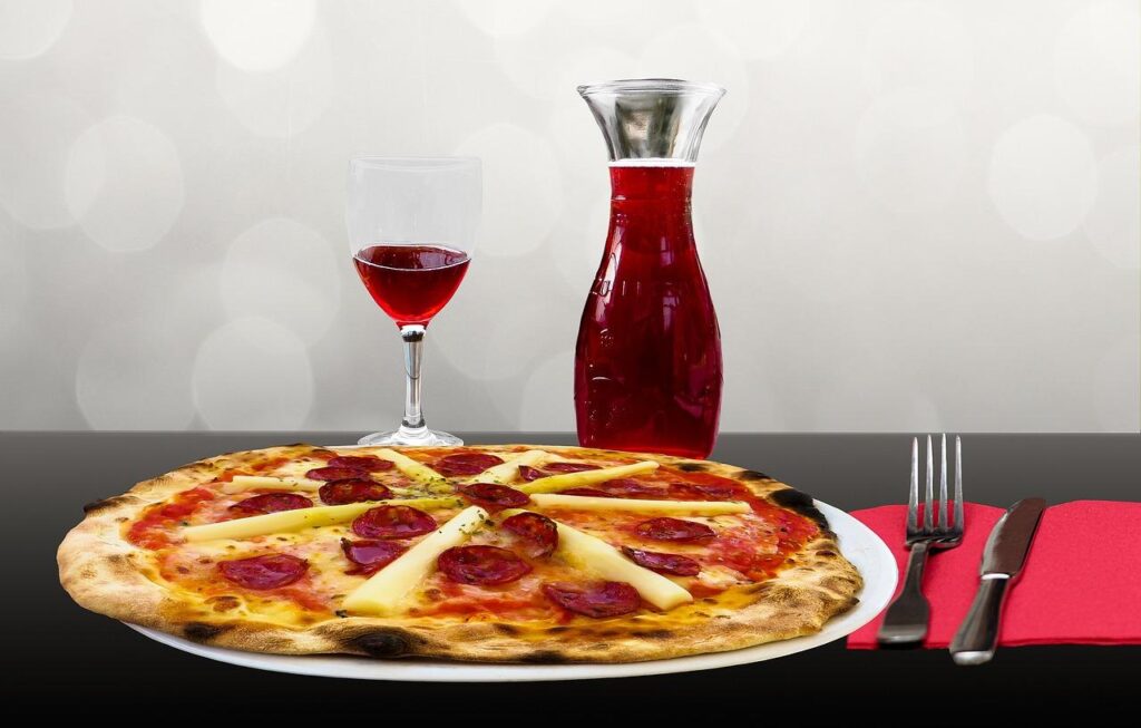 Photo of a pizza with wine glasses and bottle.