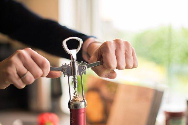 A photo of a person openeing a wine bottle.