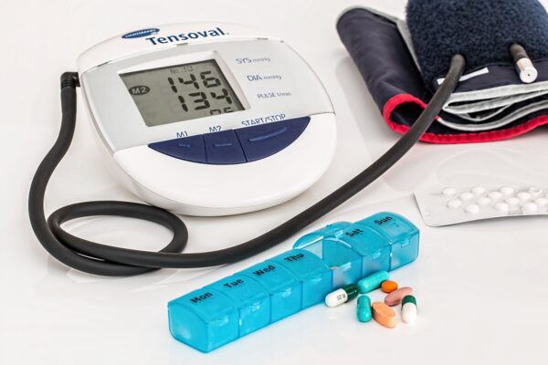 A picture of a blood pressure monitor and pills, wine health.