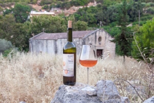 A photo of a glass and bottle of orange wine.